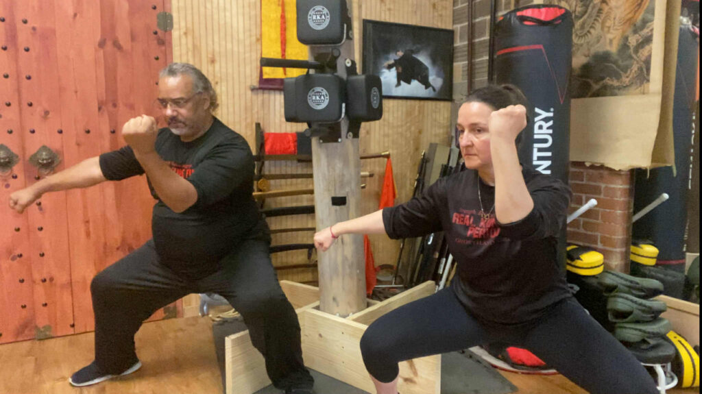 Martial arts training session emphasizing discipline and strength. Middle outward block in a horse stance.