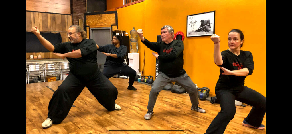 Adult martial arts students over 40 training in synchronized Kung Fu movement in Pittsburgh.